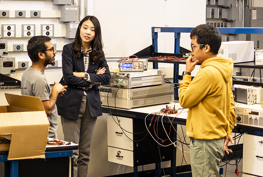 Jungwon in her lab, having a conversation with two graduate students.