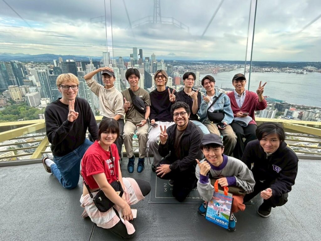 Group of people posing for a photo in the space needle with downtown Seattle in the background