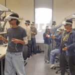 Students standing in lab wearing virtual reality headsets and holding controllers in their hands.