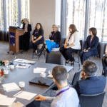 Group of people seated for panel interview in front of an audience.