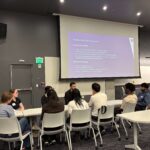 Small group of students and industry professional seated and in discussion.