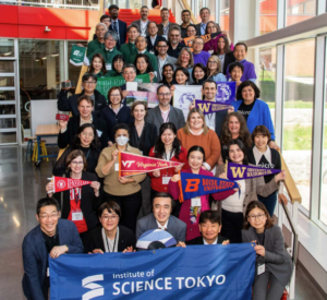 Group of UPWARDS members standing on a staircase with some holding signage and university pennants.